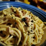 a blue bowl of chicken spaghetti parmesan seasoned with chives