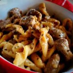 a red bowl of tender and juicy beef stroganoff