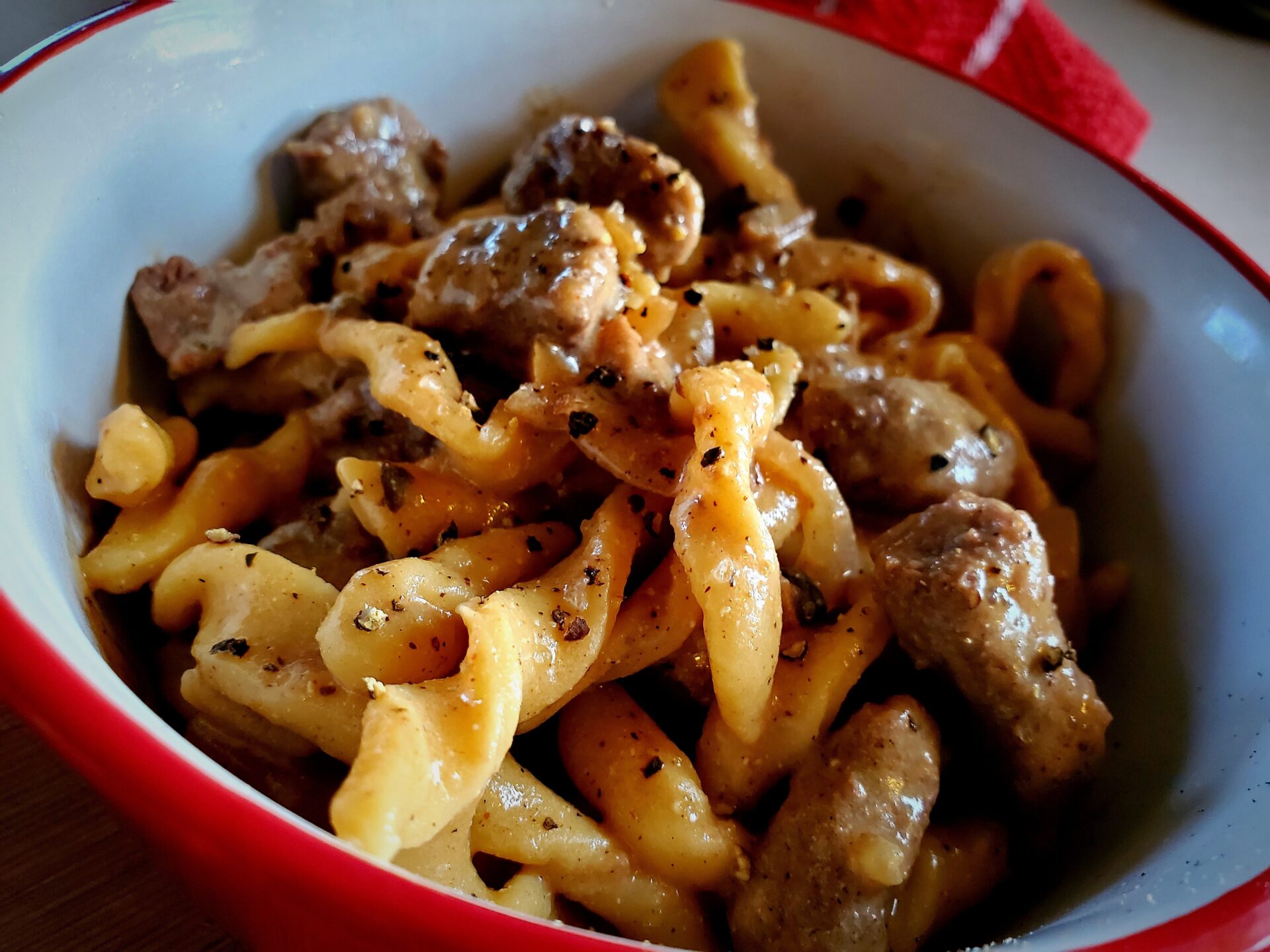 a red bowl of tender and juicy beef stroganoff