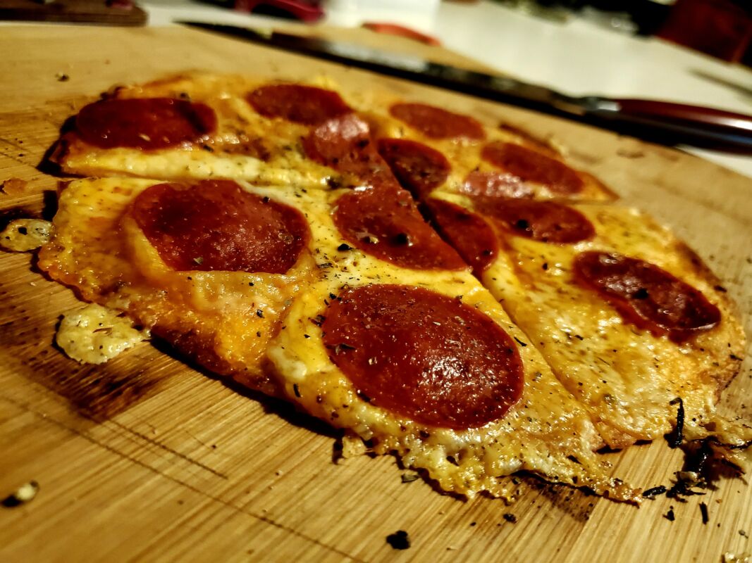 A freshly cooked tortilla pepperoni pizza on a cutting board.