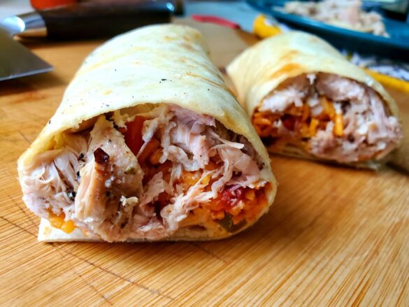 A picture of a cheesy chicken and Spanish rice burrito cut in half.